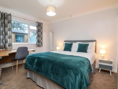 a bedroom with a bed and a desk and a window at Summerhayes in Redruth