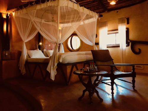una camera con letto a baldacchino e tavolo di Bakuba Lodge - Le petit hôtel du Voyageur ad Ankilibe