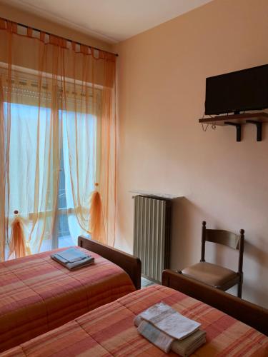 1 Schlafzimmer mit 2 Betten, einem TV und einem Fenster in der Unterkunft Hotel Villa Carla in Piana Crixia