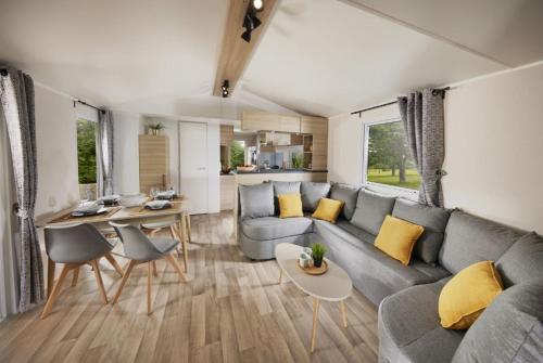 un soggiorno con divano grigio e cuscini gialli di Kokua Développement présente MOBIL HOME résidentiel toutes options camping 4 étoiles CANET a Canet-en-Roussillon