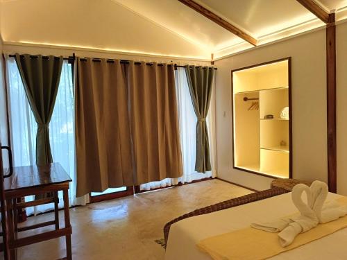 a bedroom with a mirror and a bed and a table at Kawai Duli Bungalows in El Nido