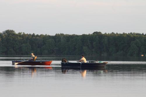 two men and a dog in boats on a lake at Ferienhaus Pirol in Zossen