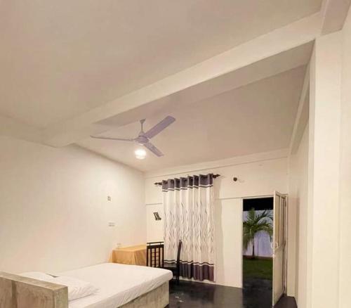 a white room with a ceiling fan and a bed at Hotel prime in Piliyandala