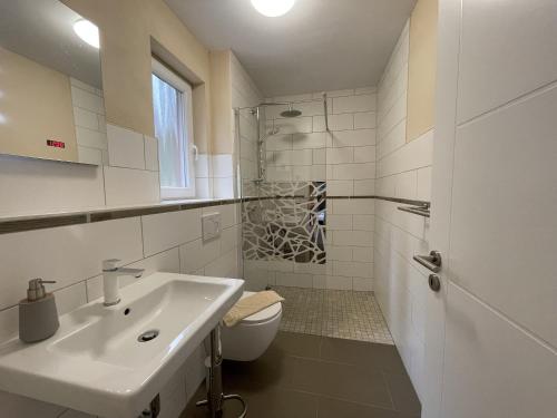 een witte badkamer met een wastafel en een toilet bij Ferienhaus Eichelhäher in Zossen