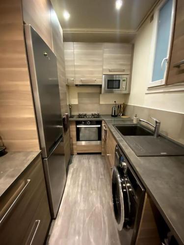une petite cuisine avec un évier et un réfrigérateur dans l'établissement Tour Eiffel - Appartement avec jardin, à Paris