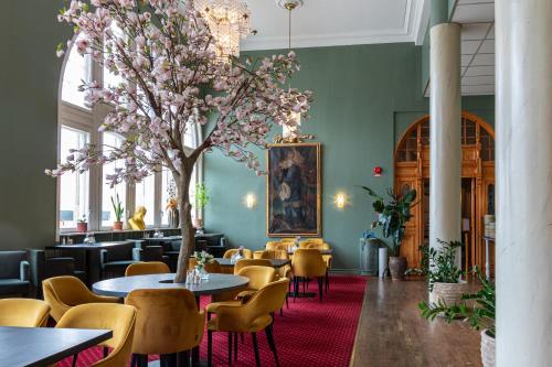 um restaurante com mesas e cadeiras e uma árvore em First Hotel Christian IV em Kristianstad