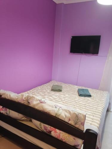 a purple room with a bed with a flat screen tv at Ariadni Apartment in Thessaloniki