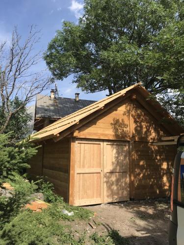 a house with a garage with a tree on top at MAISON CARAIL Névache 14 personnes in Névache