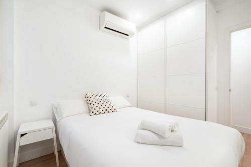 a white bedroom with a white bed and a window at apartamento exclusivo en velazquez in Madrid