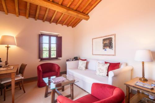 a living room with a white couch and red chairs at The Club House in Castelnuovo Berardenga