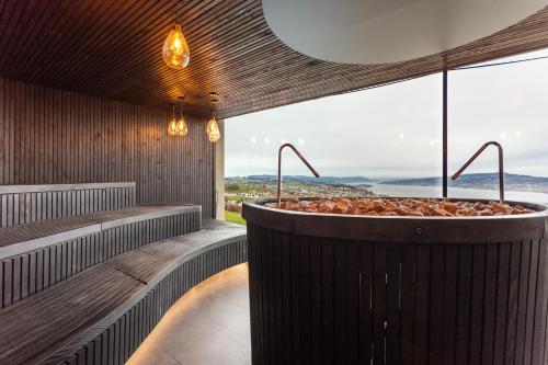 a bath tub in a room with a large window at Panorama Resort & Spa in Feusisberg