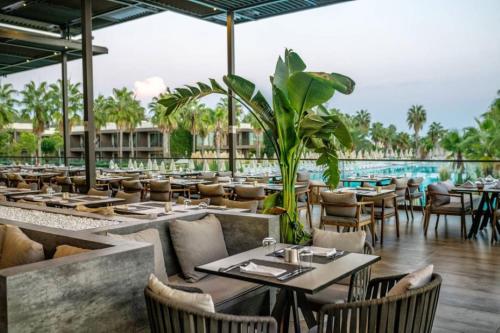 a restaurant with tables and chairs and a pool at Paloma Orenda in Side