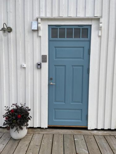 una porta blu sul lato di una casa di 1. etg i Dampskipsbrygga, Lødingen havn a Lødingen