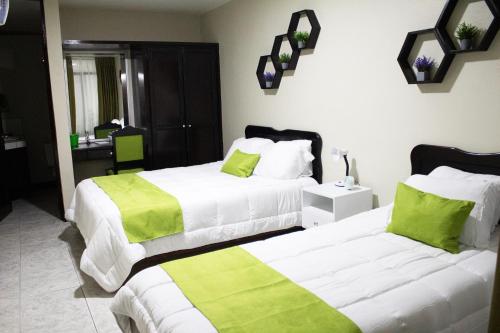 2 camas en una habitación de hotel con sábanas verdes y blancas en Hotel América Heredia en Heredia