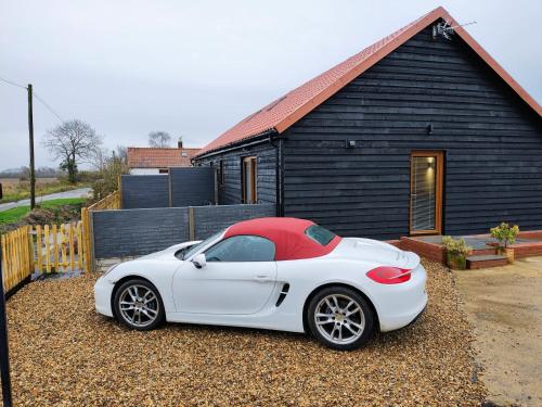 a white sports car parked in front of a house at Brooke View Barns No 1 in Norwich