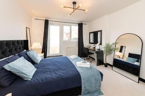 een slaapkamer met een blauw bed en een grote spiegel bij Well Equipped Apartment for Relocators and Contractors in Reading