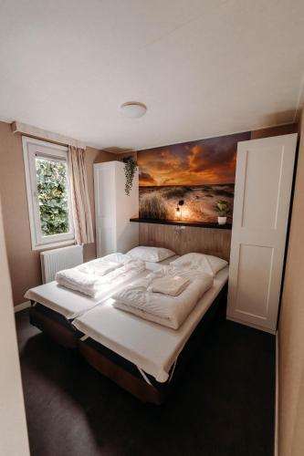 a bedroom with two beds with a painting on the wall at Chalet Tulpenweide - recreatie in Breezand