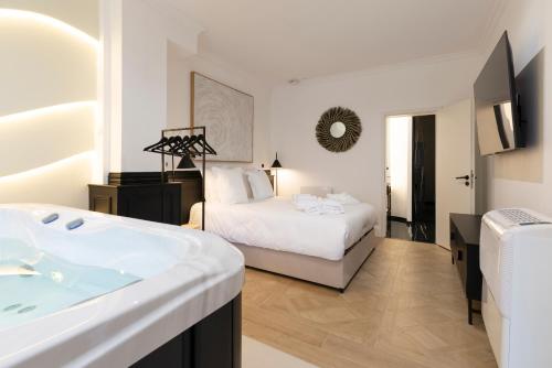 a bedroom with a bed and a tub and a sink at Le Rêve de Stanislas - Jacuzzi in Nancy
