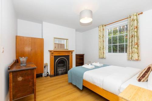 a bedroom with a large bed and a fireplace at Bright 1BR Flat wPatio in Islington, Angel in London