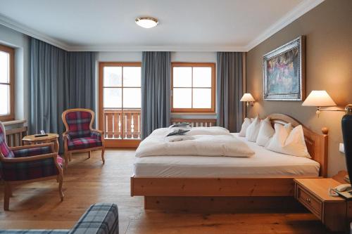 een hotelkamer met een groot bed en 2 stoelen bij Hotel Acerina Superior in Lech am Arlberg