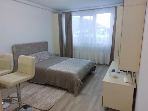 ein Schlafzimmer mit einem Bett, einem Stuhl und einem Fenster in der Unterkunft RG Garsoniera Central in Piatra Neamţ