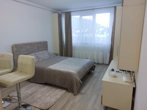 a bedroom with a bed and a chair and a window at RG Garsoniera Central in Piatra Neamţ