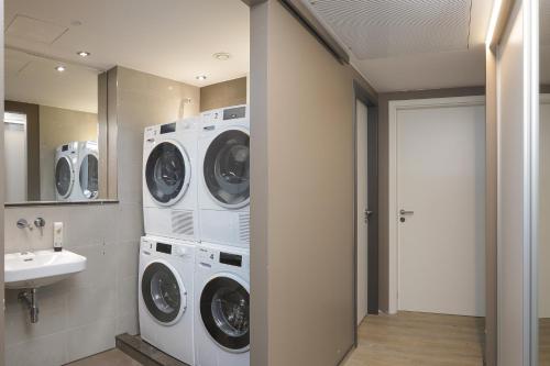 a laundry room with three washers and a sink at Hotel Stadt Lörrach in Lörrach