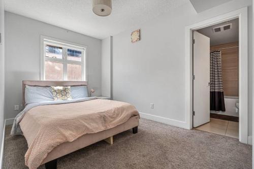 a white bedroom with a bed and a window at BowRiver view downtown 2 bedroom Downtown Calgary in Calgary