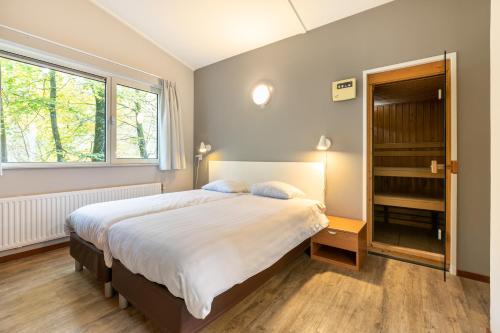 Un dormitorio con una cama grande y una ventana en Summio Parc De Berkenhorst, en Kootwijk