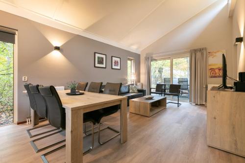 a living room with a wooden table and chairs at Summio Parc De Berkenhorst in Kootwijk