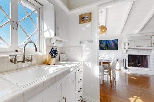 a white kitchen with a sink and a fireplace at Virginia Way Cottage in Laguna Beach
