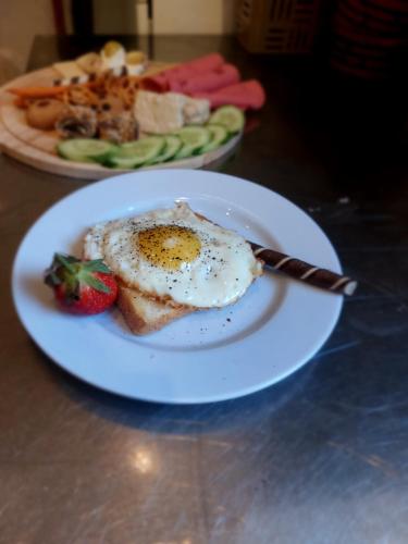 a plate with an egg and a strawberry on a table at DouDou Pyramids View Hotel in Cairo