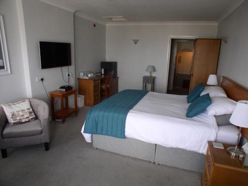 a bedroom with a bed and a chair and a television at St Magloire in Saint Aubin