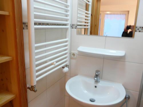 Baño blanco con lavabo y espejo en Ferienwohnung mit Seeblick - b46412, en Lychen