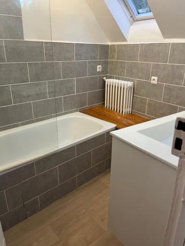a bathroom with a white bath tub and a window at Logement Romily avec vue Montagne in Le Mont-Dore