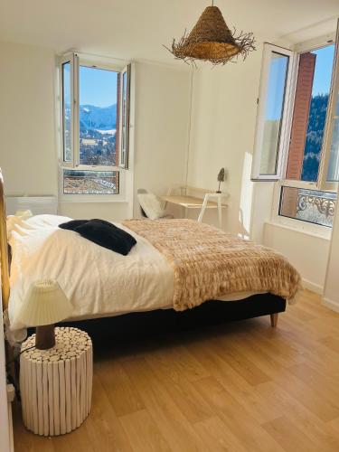 une chambre avec un lit, une table et des fenêtres dans l'établissement Logement Romily avec vue Montagne, à Le Mont-Dore