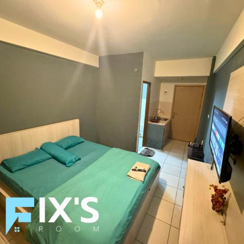 una camera con letto e TV a schermo piatto di Jasmin Park Apartemen By Fix's Room a Kedungbadak