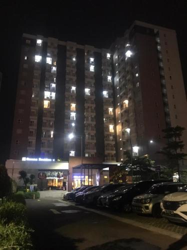 un grande edificio con auto parcheggiate in un parcheggio di notte di Jasmin Park Apartemen By Fix's Room a Kedungbadak