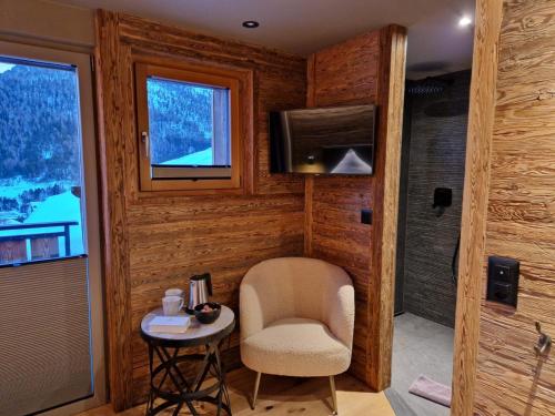 a room with a chair and a table and a television at Boutique Lodge Spycher in Saas-Fee