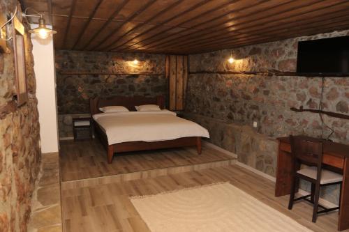 - une chambre avec un lit dans une pièce dotée de murs en pierre dans l'établissement Vila Toplika, à Kara Agach