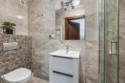 a bathroom with a toilet and a sink and a mirror at WillaByTheRiver in Poronin