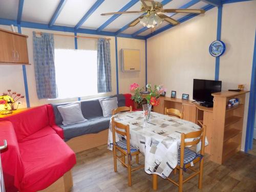 un salon avec une table et un canapé rouge dans l'établissement La Tremblade - DECOUVREZ ce MOBIL-HOME sur un TERRAIN PRIVE, à La Tremblade