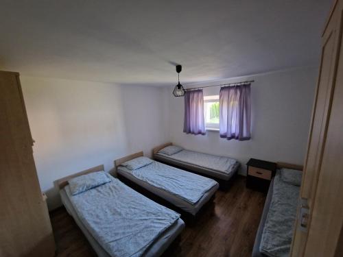Cette chambre comprend 3 lits et une fenêtre. dans l'établissement Velo Invest, à Koło