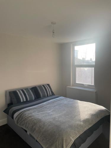 a bed in a white room with a window at Elm Road leyton in London