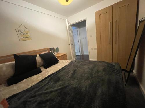 a bedroom with a large bed with black pillows at Business & Leisure City Centre 2 Bed En-suite Apartment with free parking and Netflix in Coventry