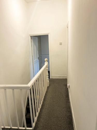 a hallway with a white stairway with a white railing and a door at Chizy’s cozy place in Liverpool