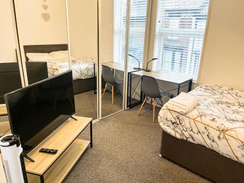 Zimmer mit einem TV, einem Bett und einem Schreibtisch. in der Unterkunft Chizy’s cozy place in Liverpool