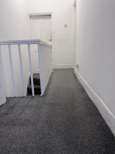 an empty hallway with a blue railing and a stair case at Chizy’s cozy place in Liverpool