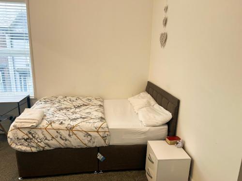 a small bedroom with a bed and a table at Chizy’s cozy place in Liverpool