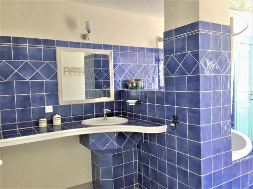 La salle de bains est pourvue de carrelage bleu, d'un lavabo et d'un miroir. dans l'établissement Maison Lou Colombier, à Comps-sur-Artuby